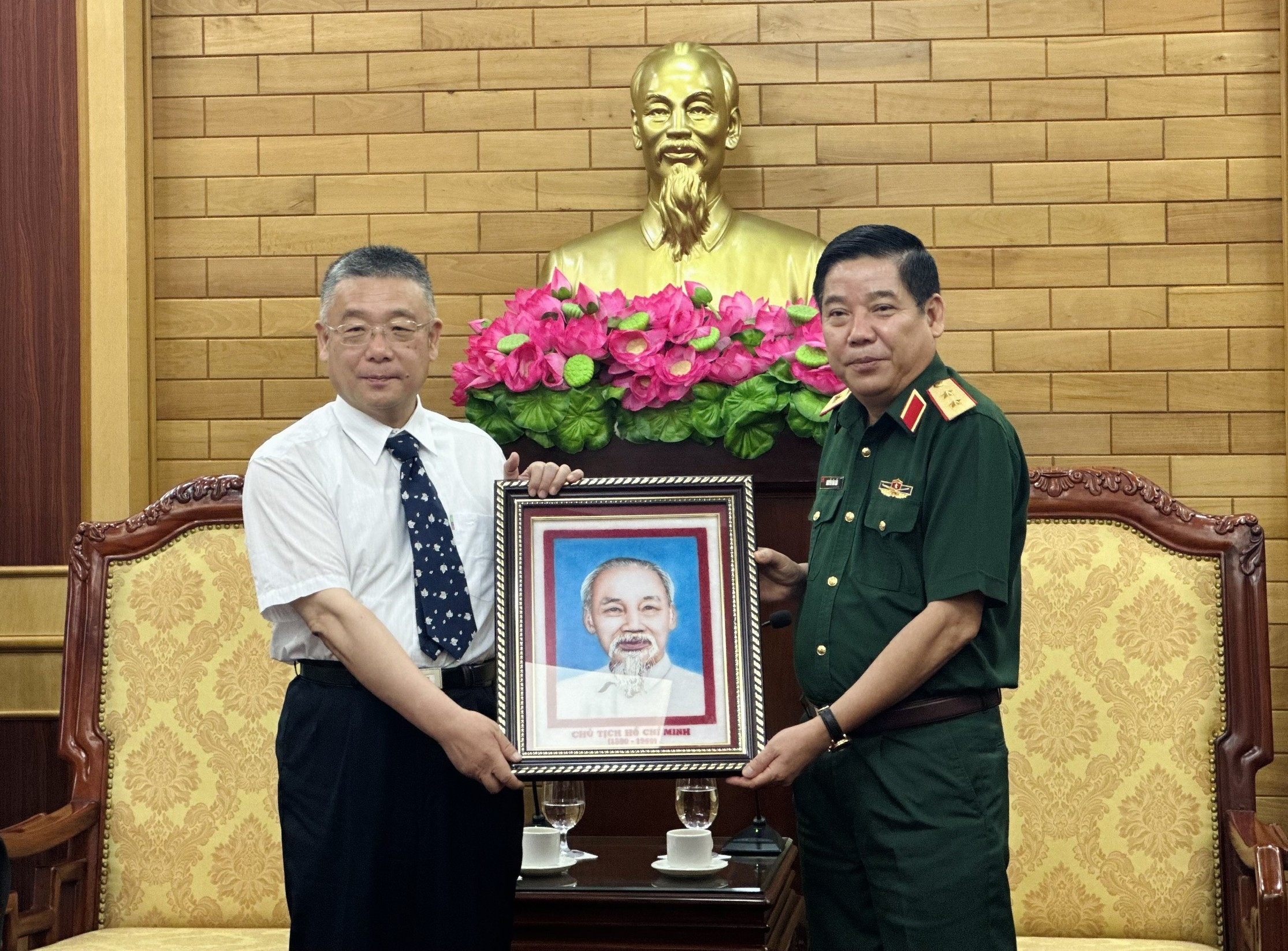  阮文熊中将（右）向韦肖毅赠送胡志明主席图片。
