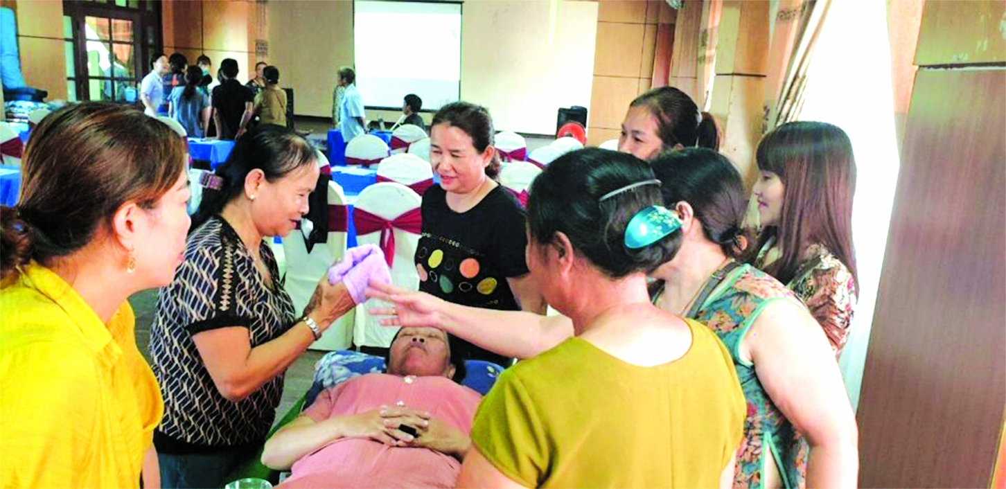 黄氏崒女士（从左到右第二个）正在培训班里为残疾人练习清洁眼、鼻、耳。（图：MCNV）