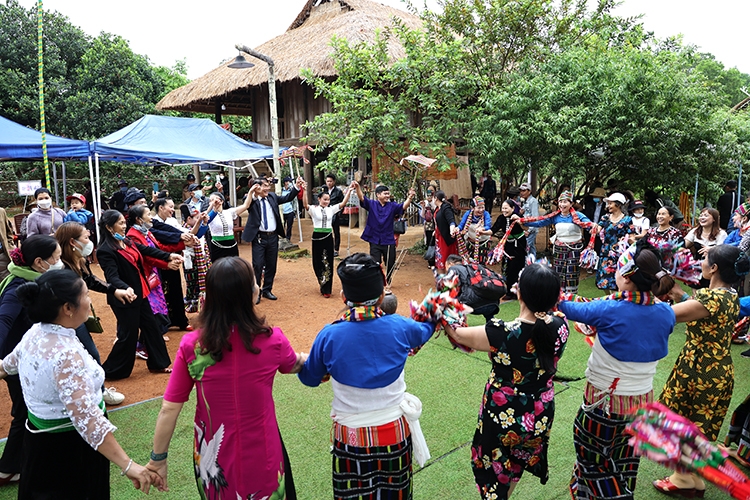 游客在越南各民族文化旅游村与泰族人民交流。