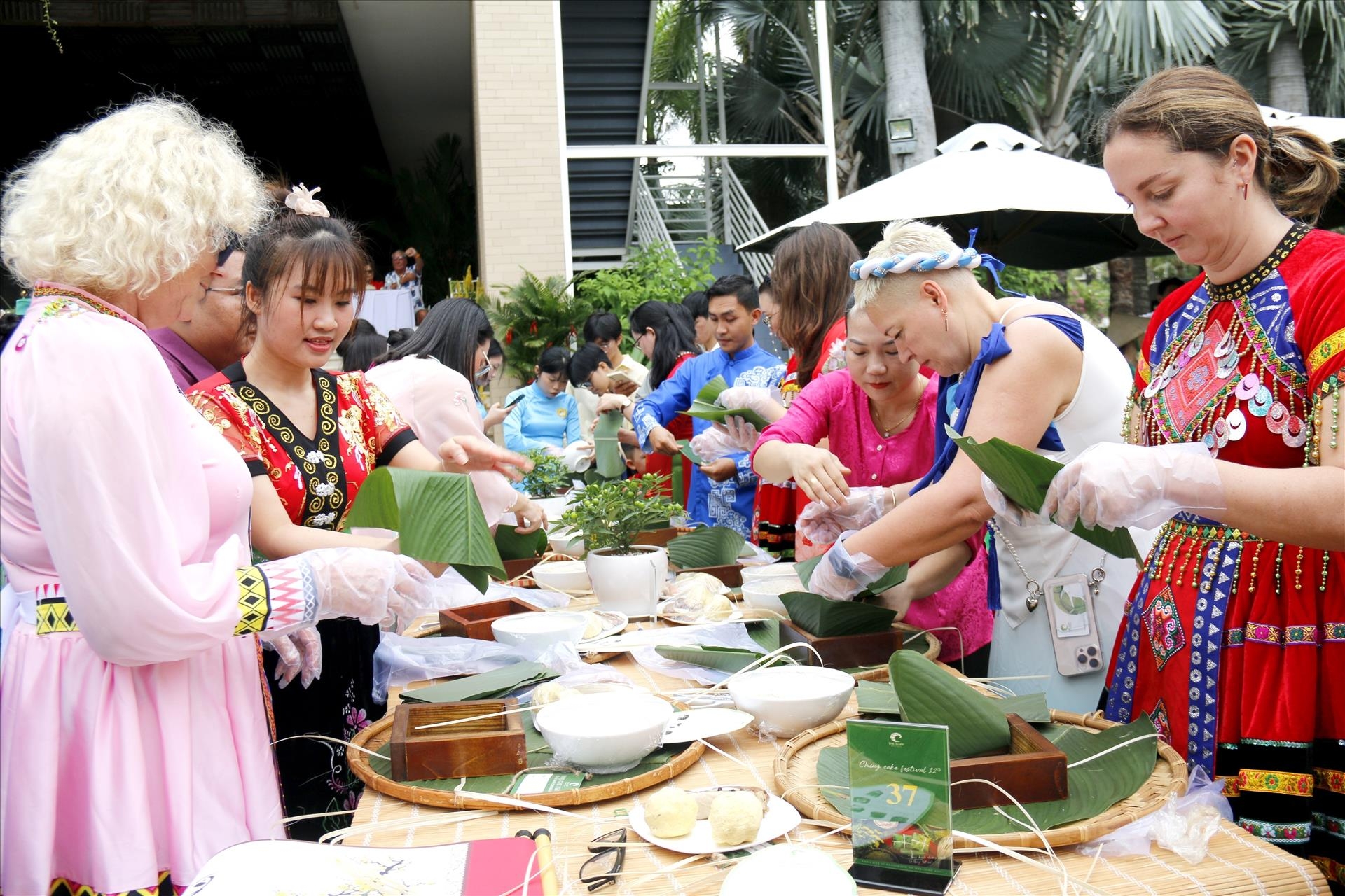 国际游客兴致勃勃地身着越南各民族服装，并在传统春节期间体验包方粽。