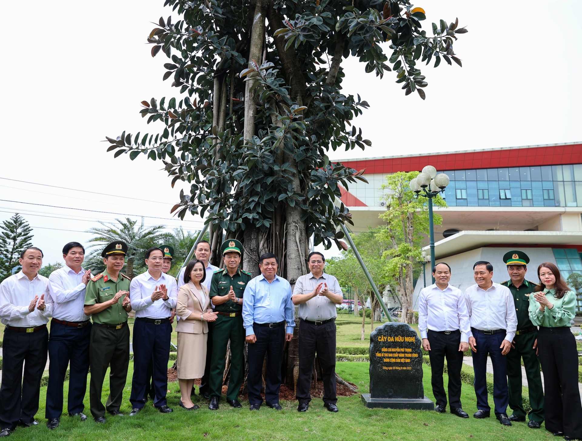 范明政总理和各位代表在阮富仲总书记于2023年8月在友谊国际口岸种植的“友谊榕树”旁边合影。