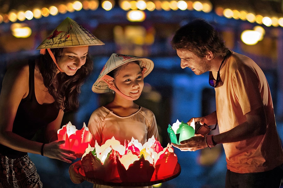 参观会安古镇的外国游客与越南儿童放河灯。